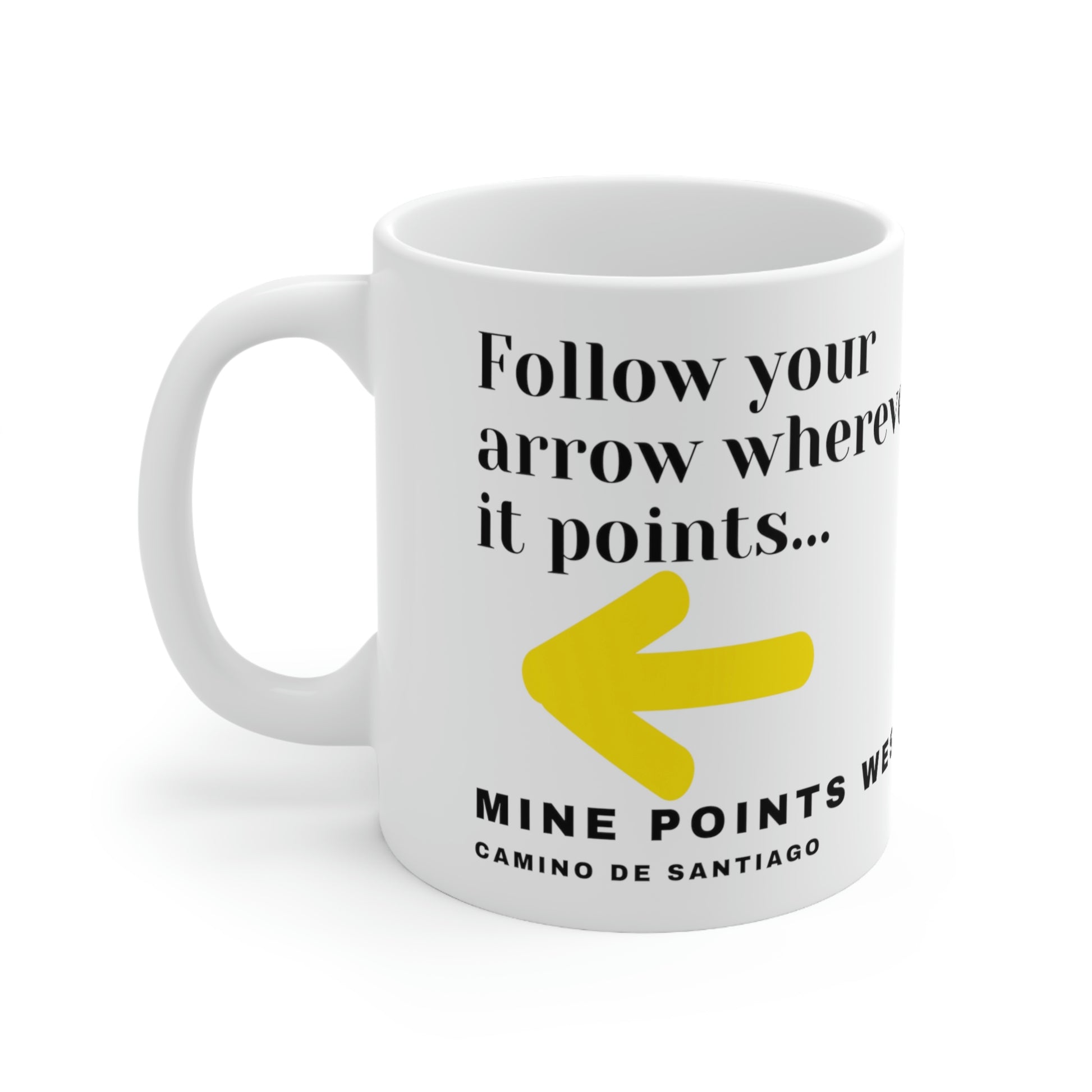 Camino Frances - This white ceramic mug has a slogan in clack letters that says, Follow your arrow wherever it points . . . With a yellow arrow below it then below that the words, Mine Points West and under that Camino de Santiago. The Mug is surrounded by white background.